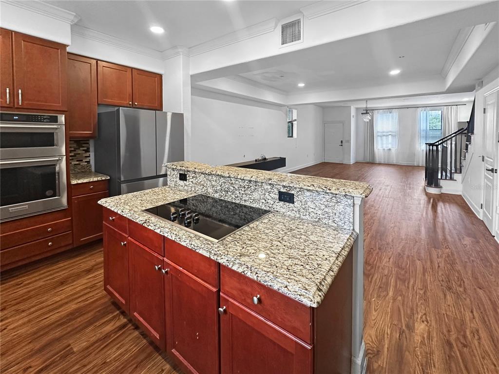 A kitchen with granite countertops and wood cabinets overlooks an open living area — 584 COPLEY LANE, ORLANDO, FL