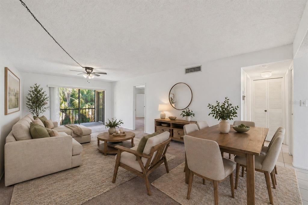 An open-concept living and dining area with neutral furniture, a wooden table, and balcony access — 130 CYPRESS LANE UNIT 130, OLDSMAR, FL
