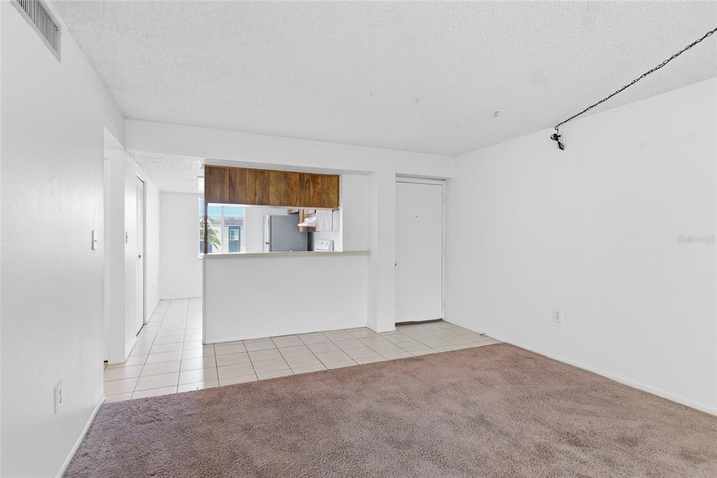 An interior view shows a living room with brown carpet and a tiled kitchen area — 130 CYPRESS LANE UNIT 130, OLDSMAR, FL