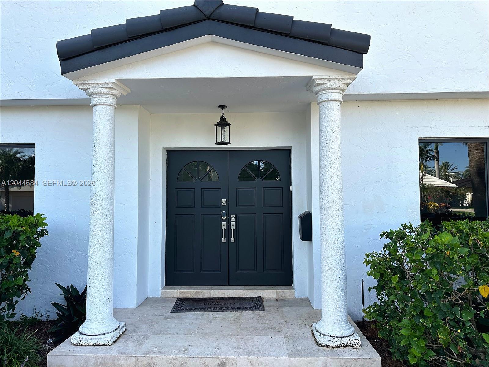 A white house entrance features a dark double door, two columns, and a tiled porch — 2445 SE 8th St, Pompano Beach FL 33062, POMPANO BEACH, FL