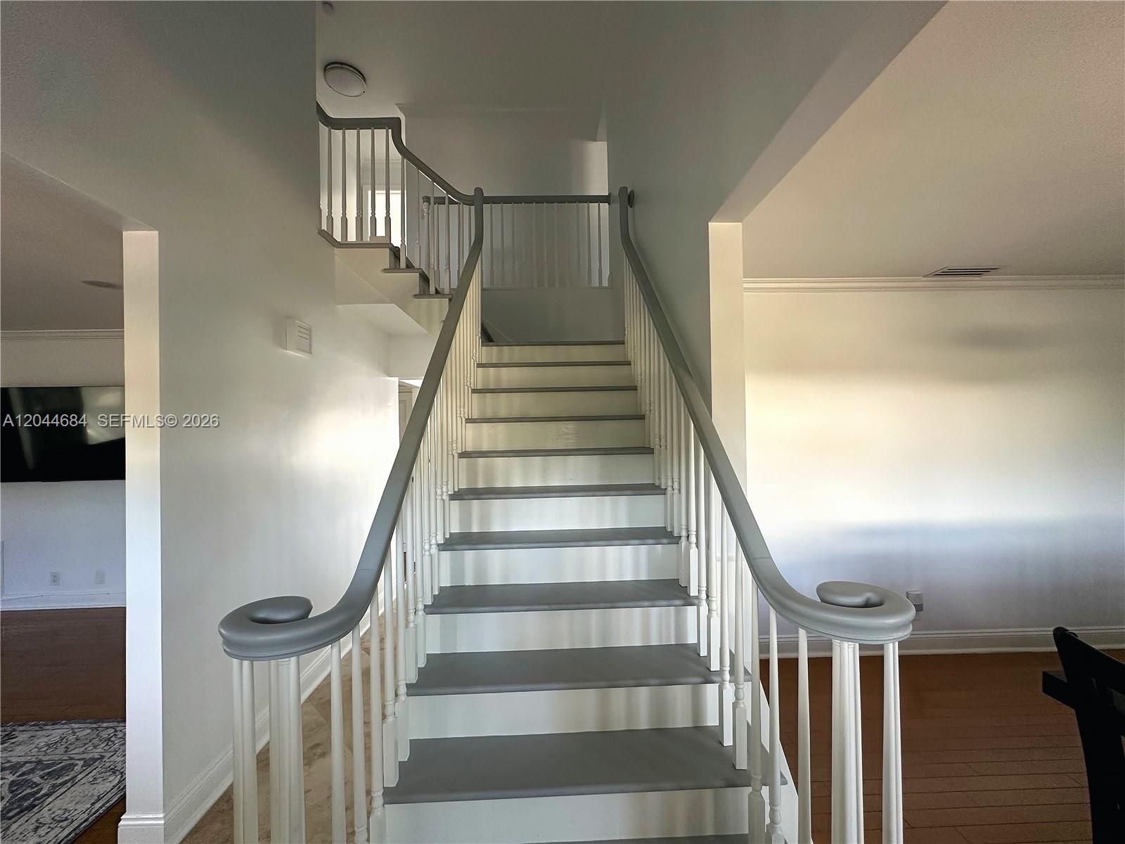 A staircase with gray treads and white railings leads to an upper landing — 2445 SE 8th St, Pompano Beach FL 33062, POMPANO BEACH, FL
