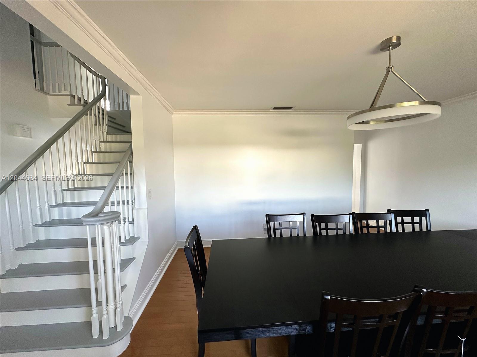 A dining room features a black table, chairs, and a staircase with white railings — 2445 SE 8th St, Pompano Beach FL 33062, POMPANO BEACH, FL