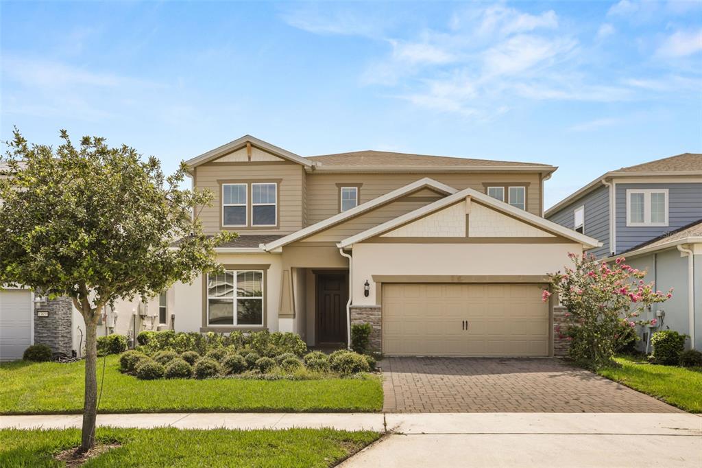 A two-story suburban house with a tan exterior, a two-car garage, and a paved driveway — 13865 DESTIN BEACH LANE, ORLANDO, FL