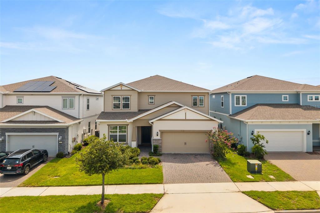 A two-story suburban house with a tan exterior, a two-car garage, and a paved driveway — 13865 DESTIN BEACH LANE, ORLANDO, FL