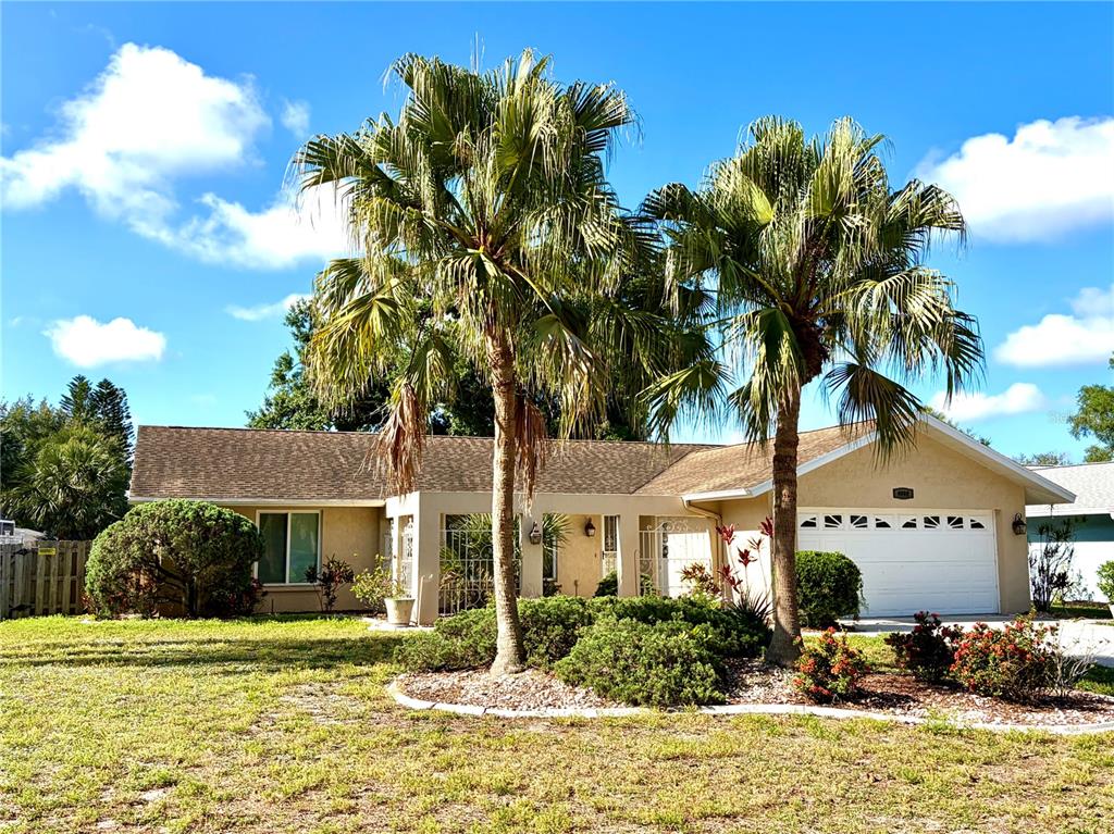 A single-story house with a white garage, two palm trees, and a landscaped front yard — 4892 GREENCROFT ROAD, SARASOTA, FL