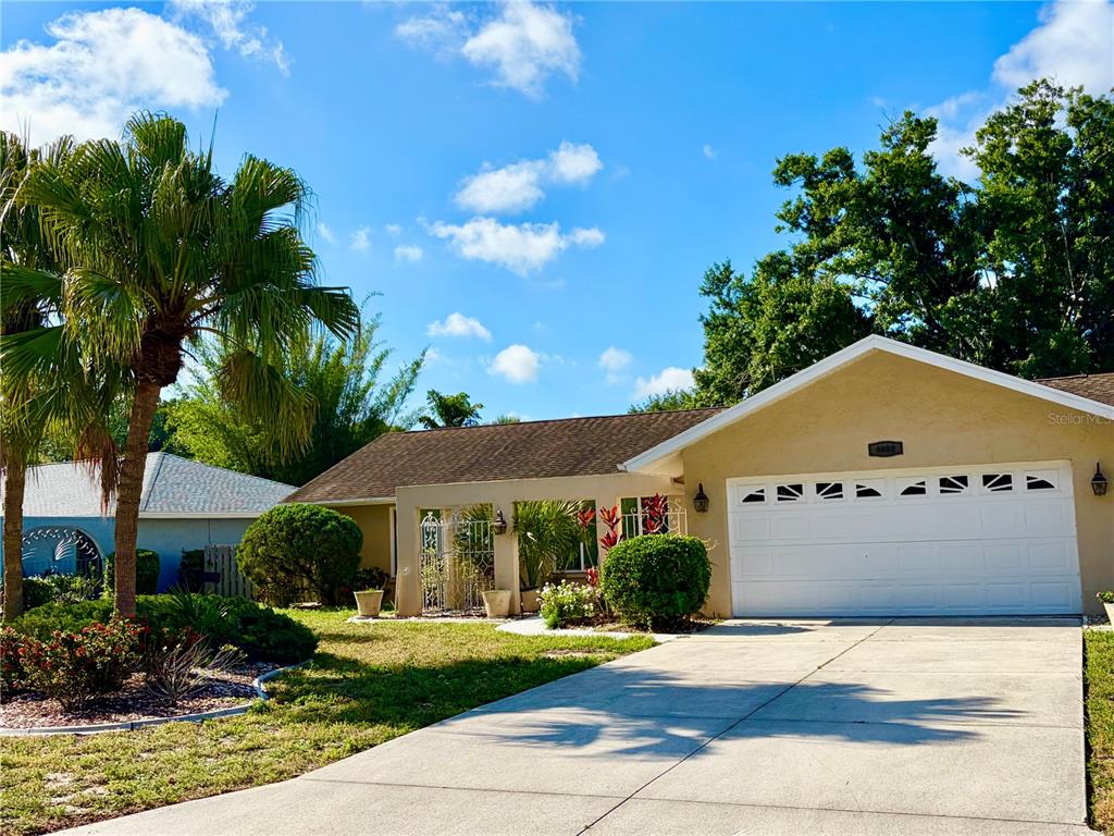 A single-story house with a white garage door, a palm tree, and a landscaped yard — 4892 GREENCROFT ROAD, SARASOTA, FL