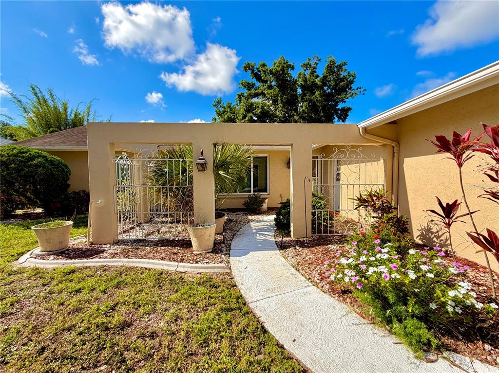 A concrete walkway leads through a decorative metal gate to the entrance of a house — 4892 GREENCROFT ROAD, SARASOTA, FL