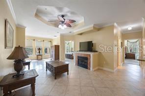 A living room with tile flooring, a fireplace, a ceiling fan, and large windows — 2724 VIA MURANO UNIT 630, CLEARWATER, FL