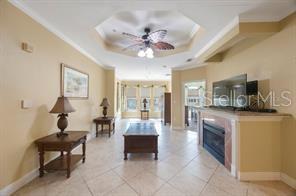 A living room features tile flooring, a tray ceiling with a fan, and a fireplace — 2724 VIA MURANO UNIT 630, CLEARWATER, FL