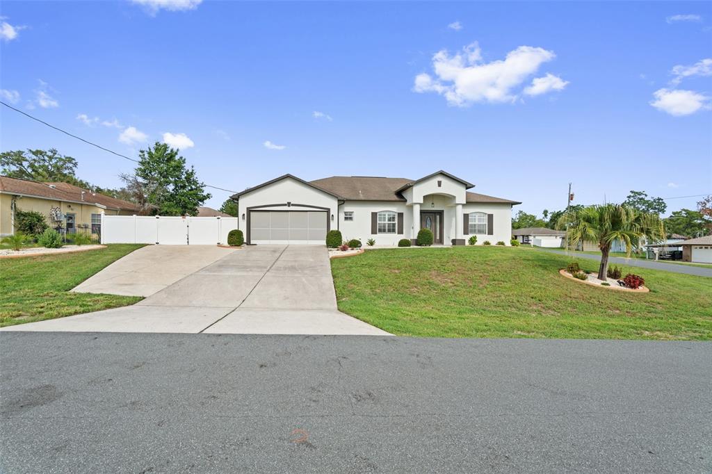 A single-story house with a white exterior, a two-car garage, and a concrete driveway — 3059 HOBAN AVENUE, SPRING HILL, FL