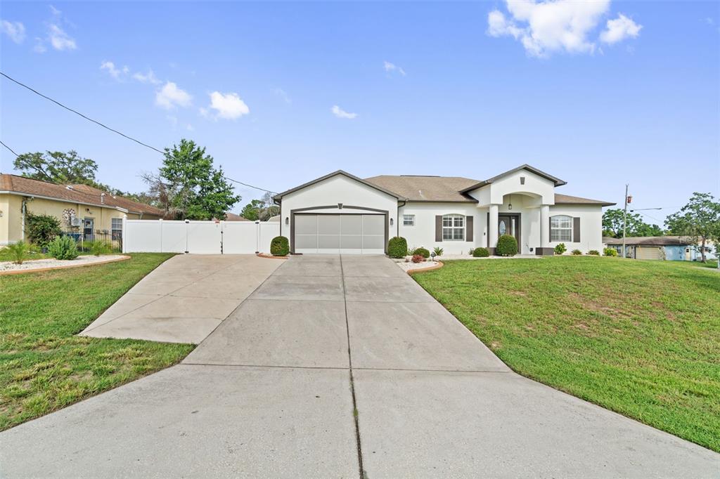 A single-story house with a concrete driveway, a two-car garage, and a white fence — 3059 HOBAN AVENUE, SPRING HILL, FL