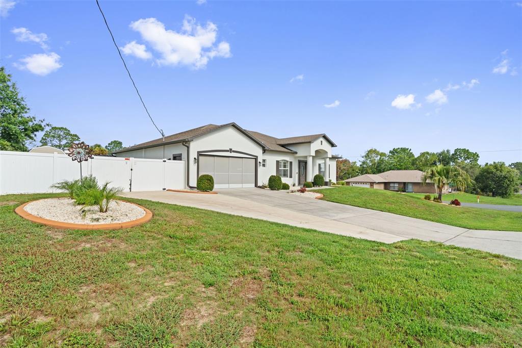A single-story house with a concrete driveway, a white fence, and a landscaped front yard — 3059 HOBAN AVENUE, SPRING HILL, FL