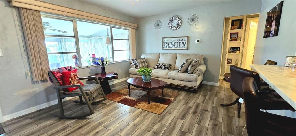 A living room features a beige sofa, a rocking chair, and wood-look tile flooring — 229 RAYMOND AVENUE, FROSTPROOF, FL