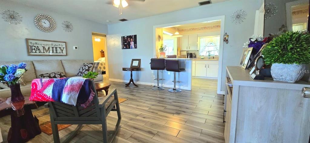 A living room with light wood-look flooring opens to a kitchen with a breakfast bar — 229 RAYMOND AVENUE, FROSTPROOF, FL