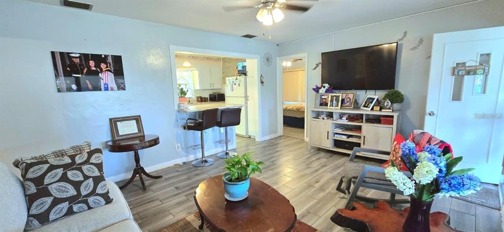 A living room features light wood-look flooring, a television console, and an open kitchen pass-through — 229 RAYMOND AVENUE, FROSTPROOF, FL