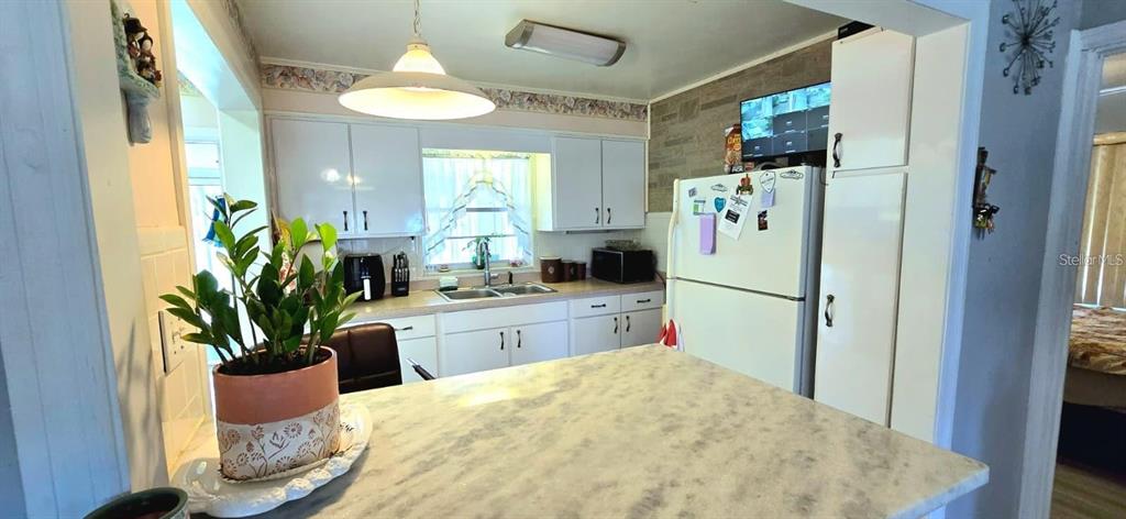 A kitchen features white cabinets, a marble-patterned countertop, and a white refrigerator — 229 RAYMOND AVENUE, FROSTPROOF, FL