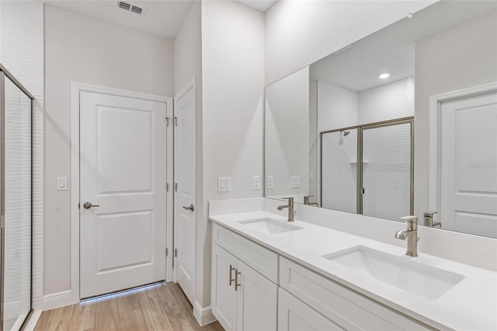 A modern bathroom features a double vanity with white cabinets, quartz countertops, and a mirror — 6225 SW 97TH STREET, OCALA, FL