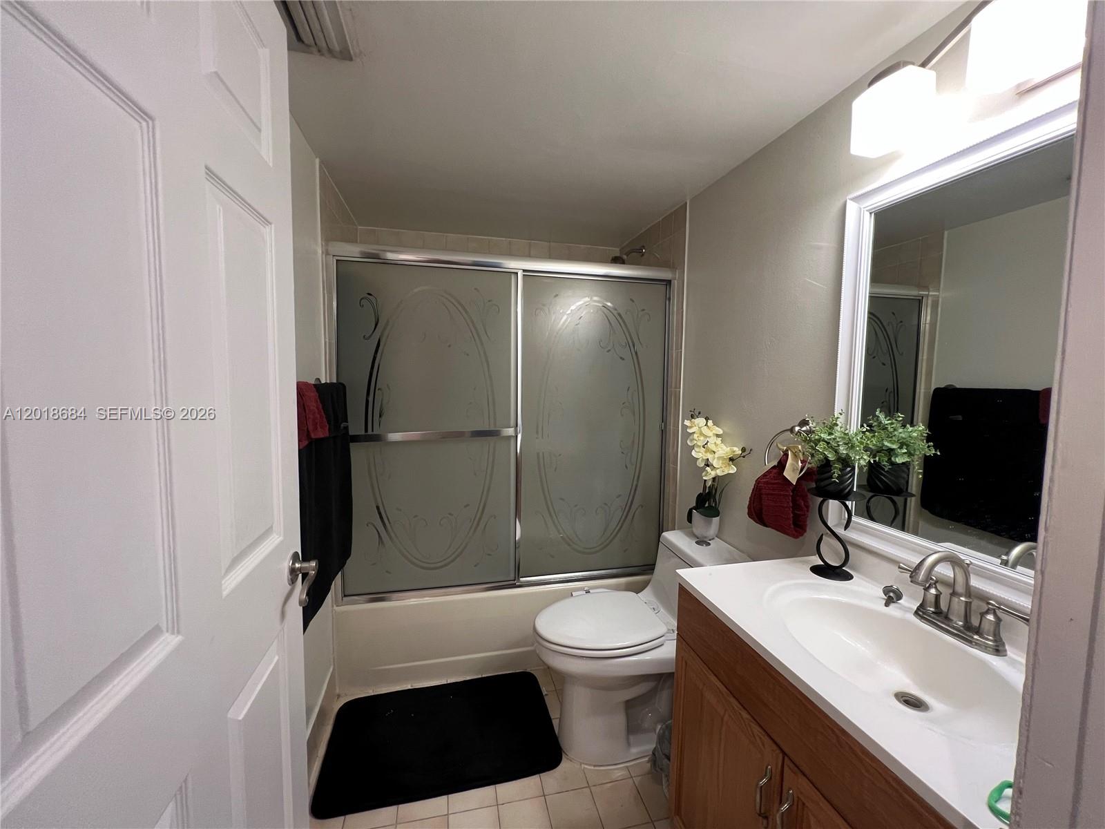 A bathroom features a vanity, toilet, and a shower-tub combination with frosted glass sliding doors — 2075 SW 122nd Ave # 207, Miami FL 33175, MIAMI, FL