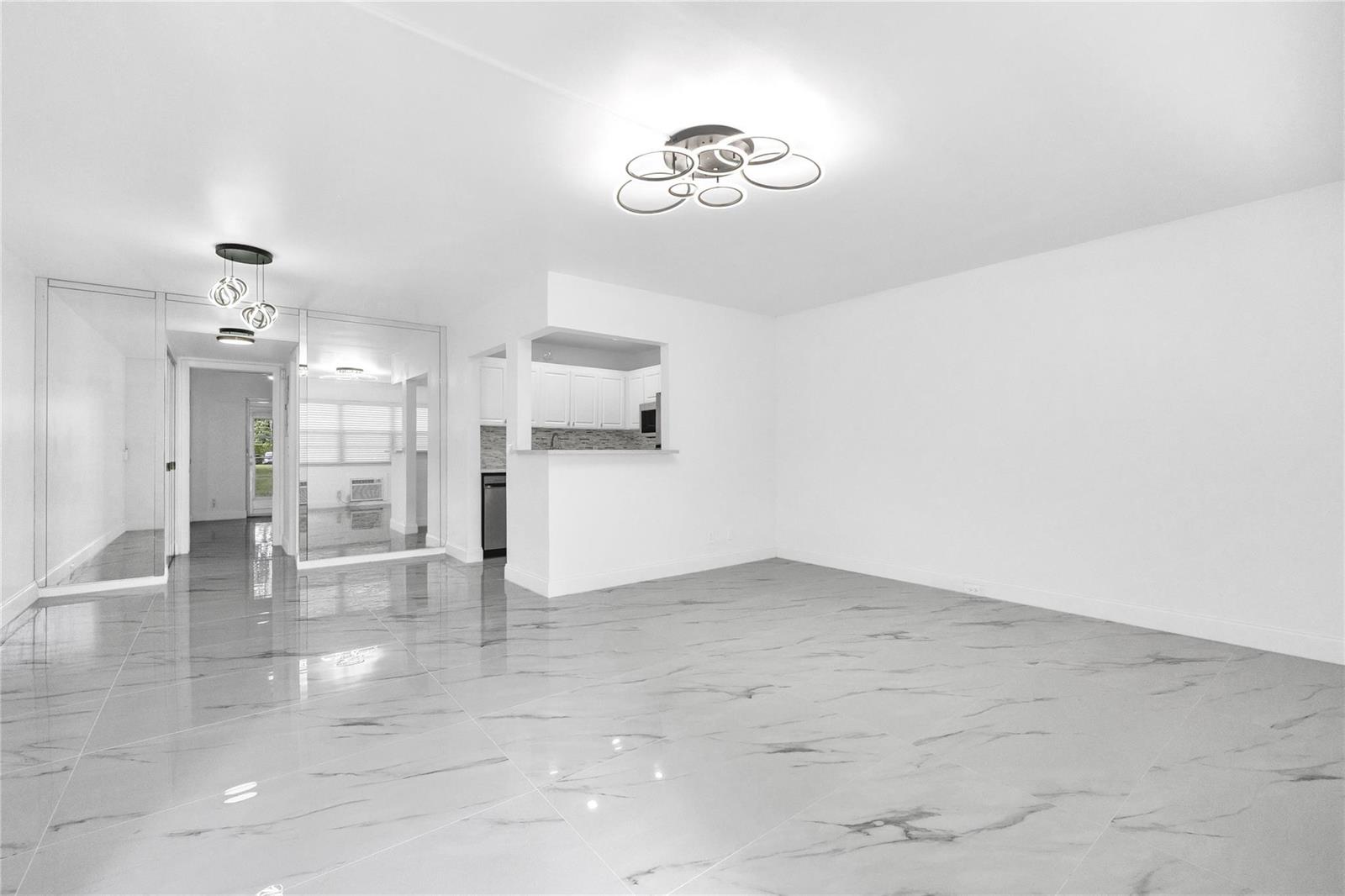 A bright, open-concept living area features white walls, a modern light fixture, and marble-look flooring — 242 Tilford L # L, Deerfield Beach FL 33442, DEERFIELD BEACH, FL