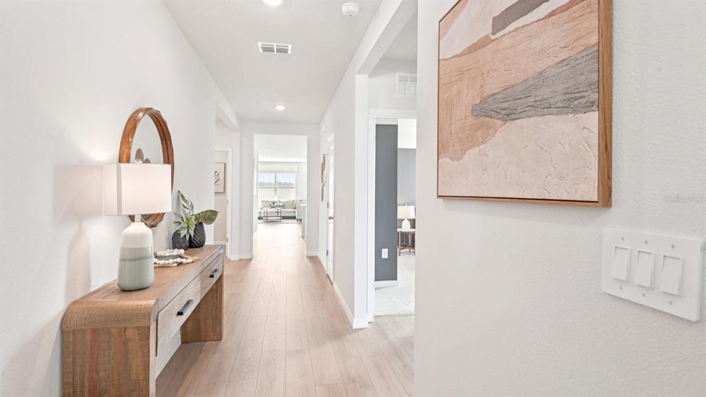 A hallway features light wood flooring, a console table with a lamp, and wall art — 1565 SOURWOOD DRIVE, RUSKIN, FL