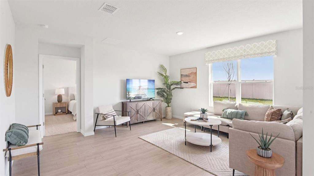 A bright living room features light wood flooring, a sectional sofa, and a television console — 1565 SOURWOOD DRIVE, RUSKIN, FL