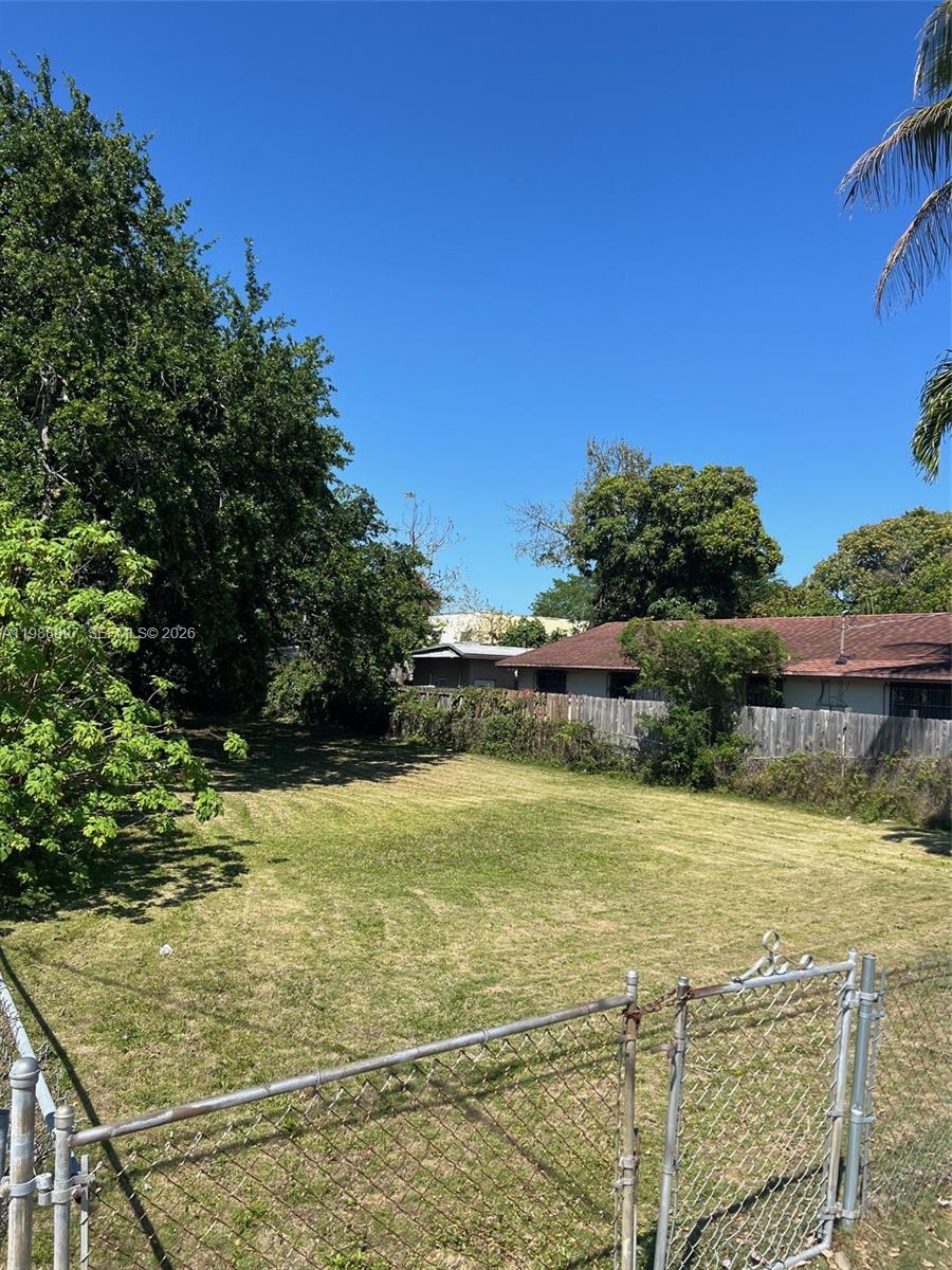 A grassy, fenced-in vacant lot sits adjacent to a residential house and mature trees — 267 NW 31st St, Miami FL 33127, MIAMI, FL