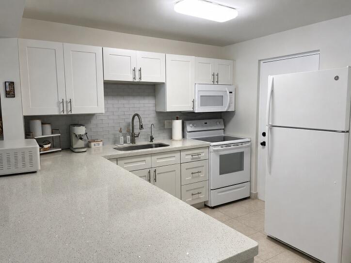 A kitchen with white cabinets, quartz countertops, a subway tile backsplash, and white appliances — 2307 S Cypress Bend Drive # 207a, Pompano Beach FL 33069, POMPANO BEACH, FL
