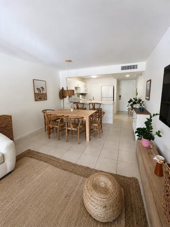 An open-concept dining area and kitchen feature light wood furniture, tile flooring, and white walls — 2307 S Cypress Bend Drive # 207a, Pompano Beach FL 33069, POMPANO BEACH, FL
