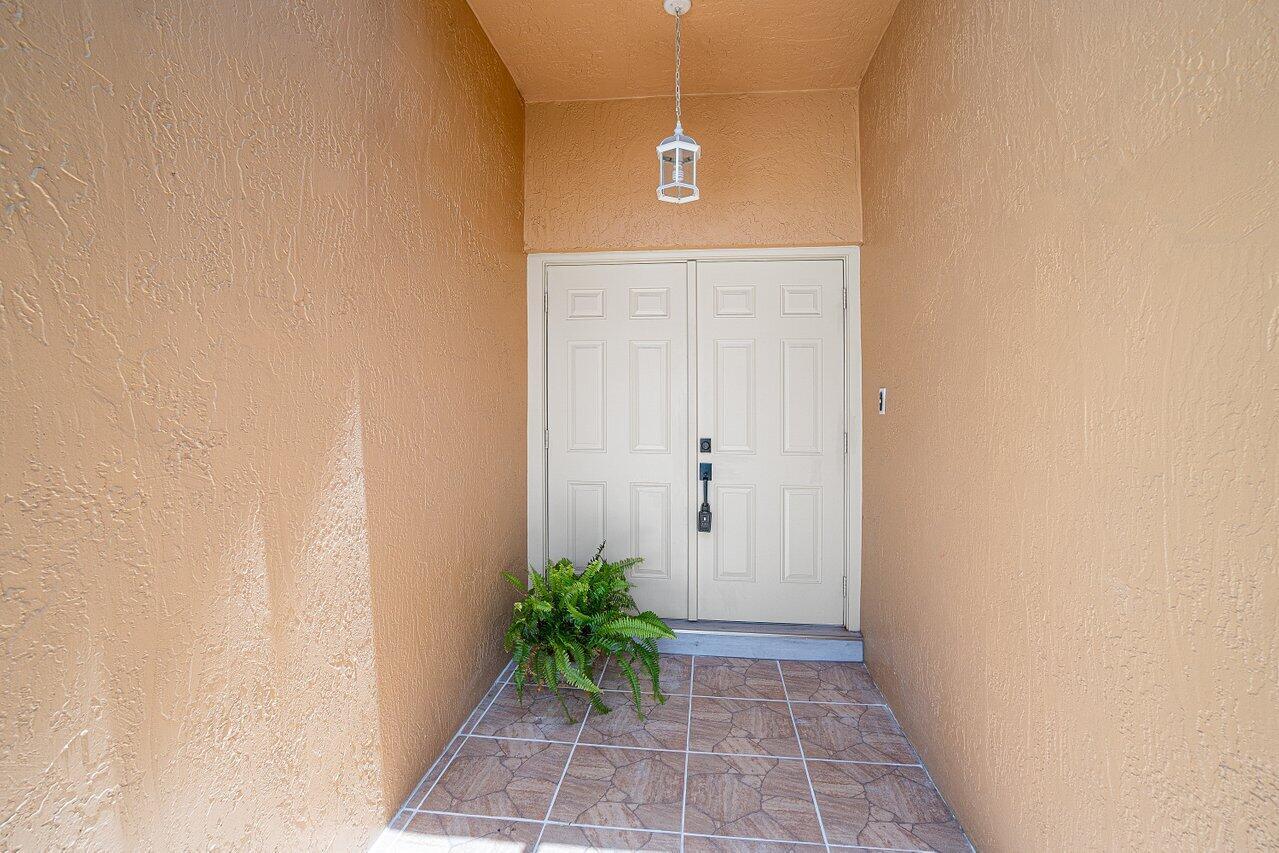 A covered entryway features double white doors, a hanging lantern, and tiled flooring — 6930 NW 2nd Terrace, Boca Raton FL 33487, BOCA RATON, FL
