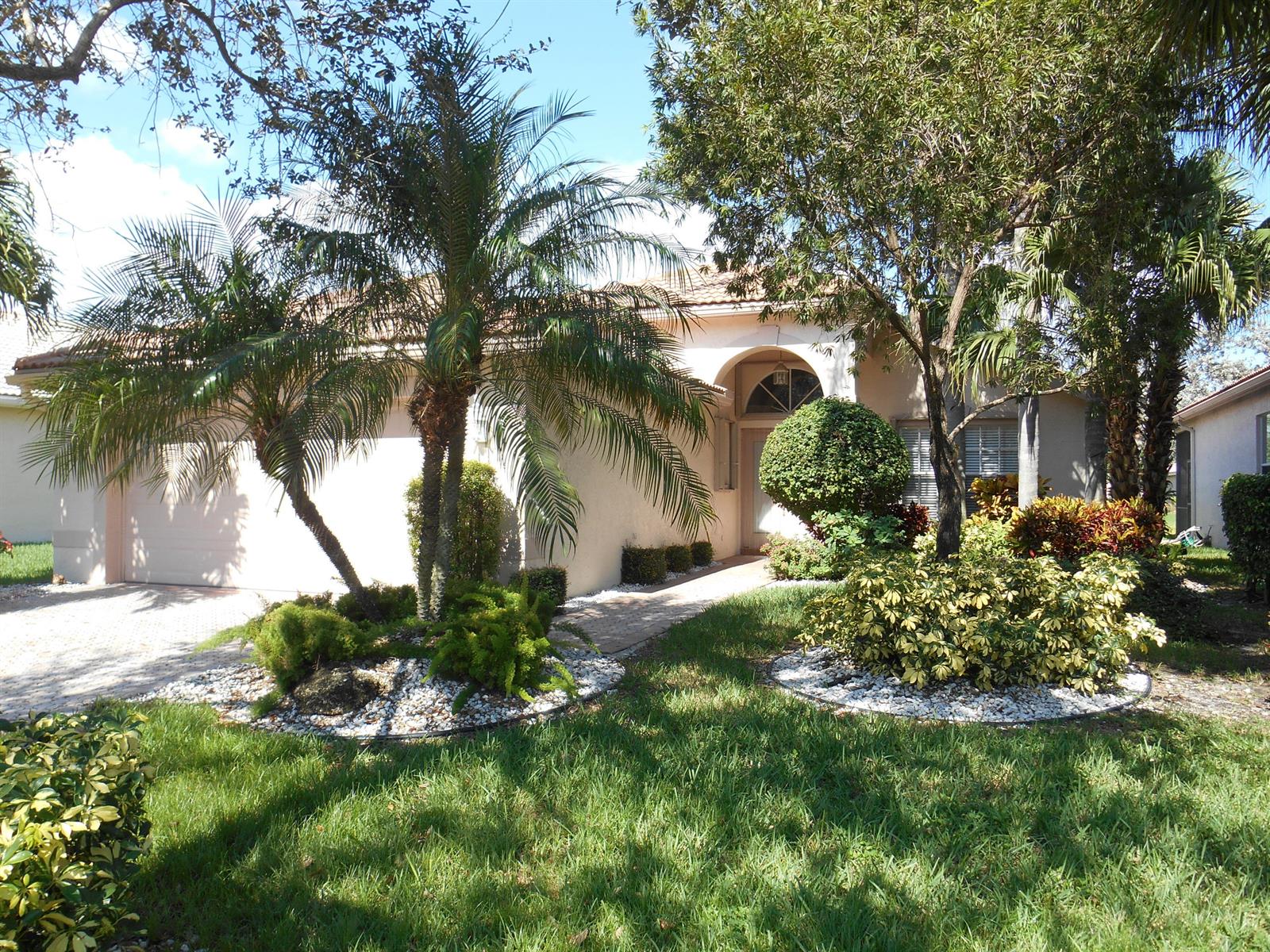 A single-story house with a beige stucco exterior, a palm tree, and landscaped front yard — 7387 Tonga Court, Boynton Beach FL 33437, BOYNTON BEACH, FL