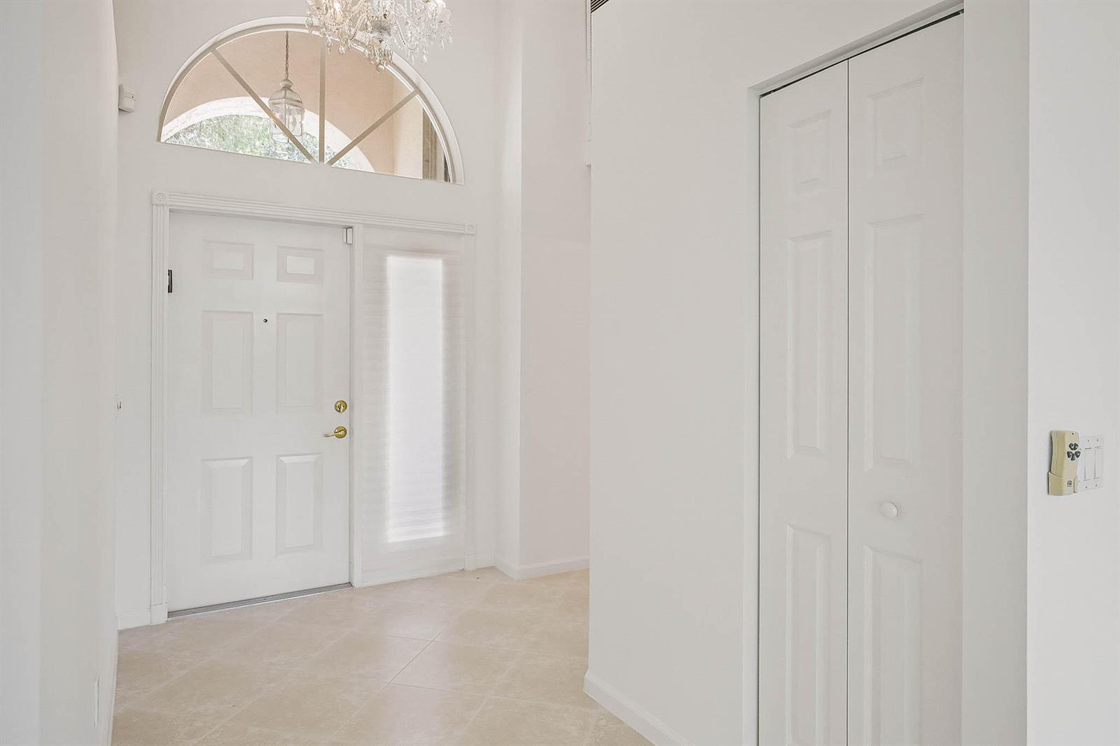 A bright entryway features a white front door, a tall arched window, and tiled flooring — 7387 Tonga Court, Boynton Beach FL 33437, BOYNTON BEACH, FL
