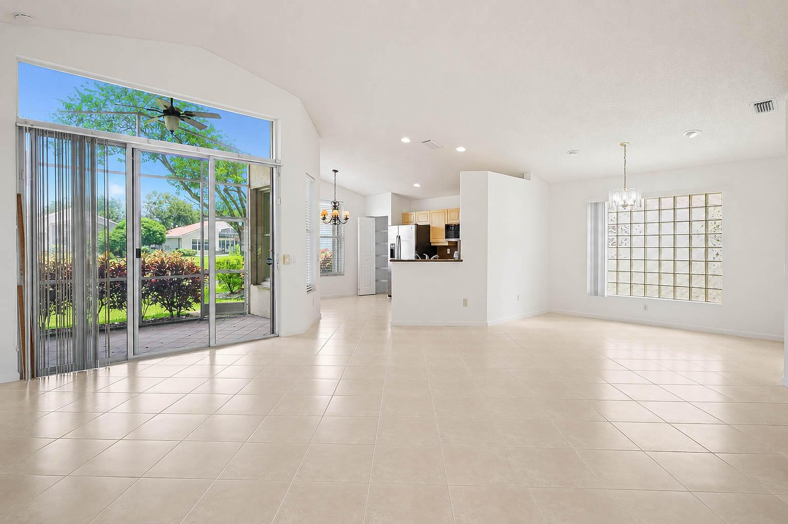 An open-concept living area features light tile flooring, a glass block window, and sliding doors — 7387 Tonga Court, Boynton Beach FL 33437, BOYNTON BEACH, FL