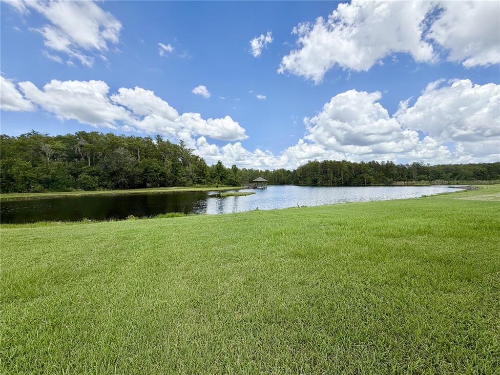 A grassy lawn slopes down toward a lake with a small gazebo in the distance — 3805 SPRINGLAKE VILLAGE COURT, KISSIMMEE, FL