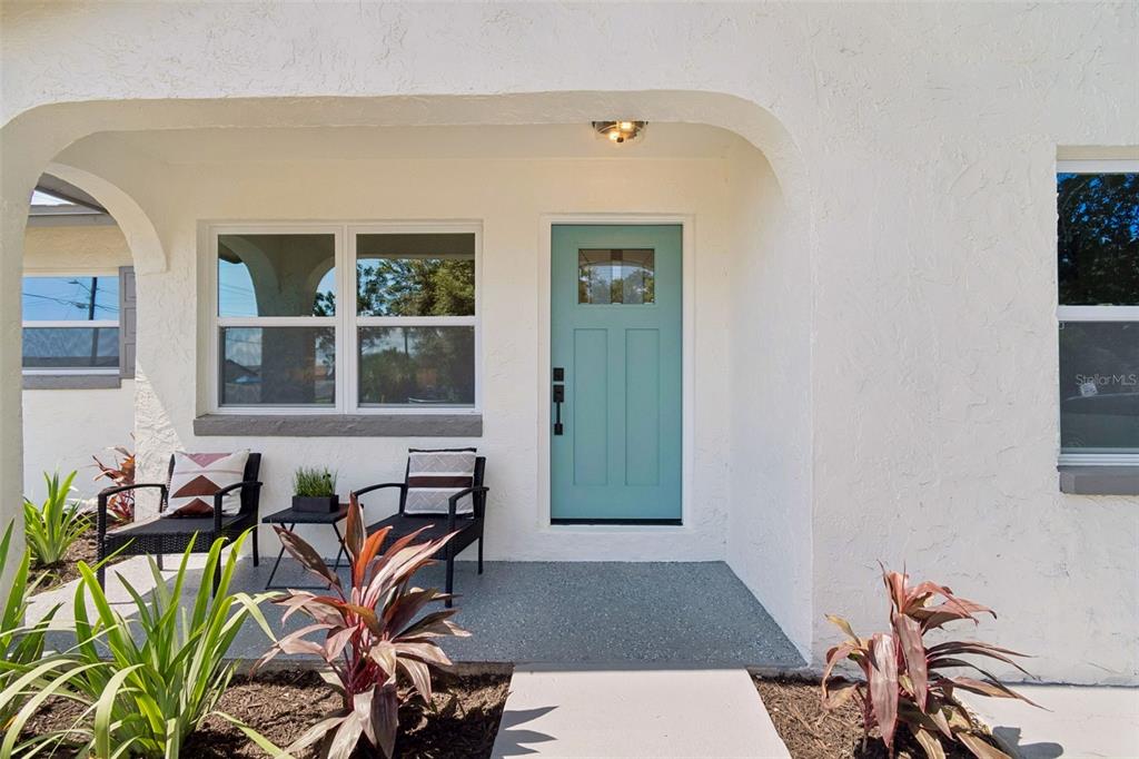 A front porch features a teal door, two chairs, and a small table — 5802 12TH AVENUE S, TAMPA, FL