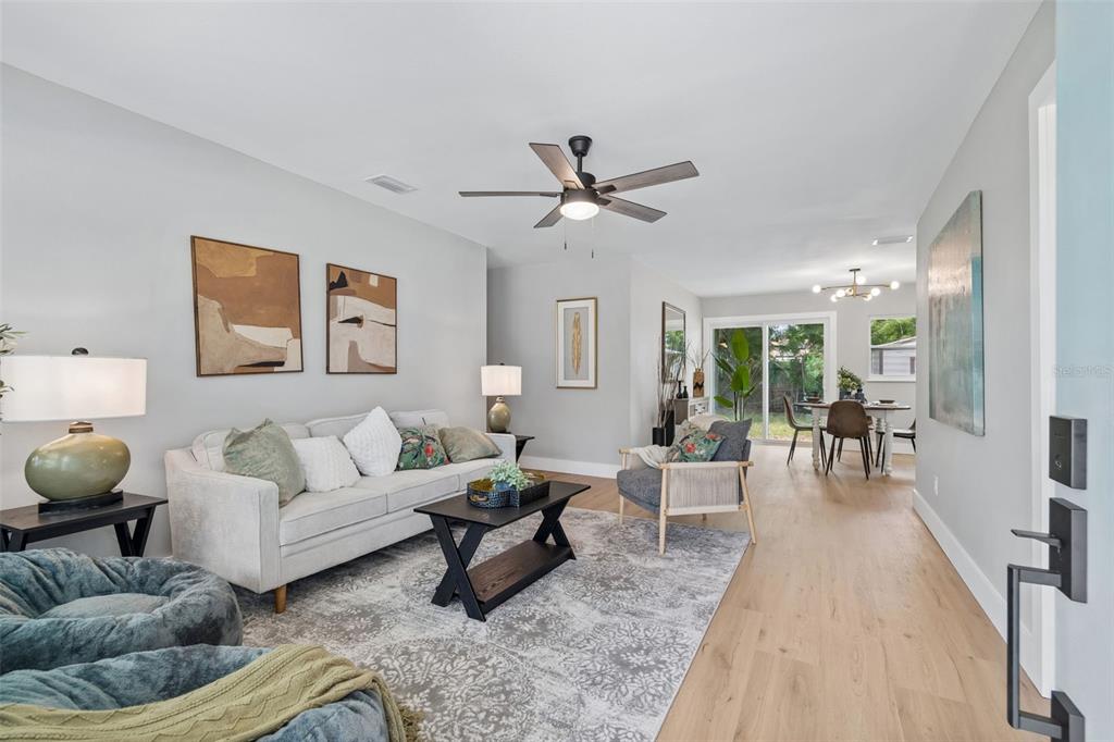 A living room features a light gray sofa, a coffee table, and wood-look flooring — 5802 12TH AVENUE S, TAMPA, FL
