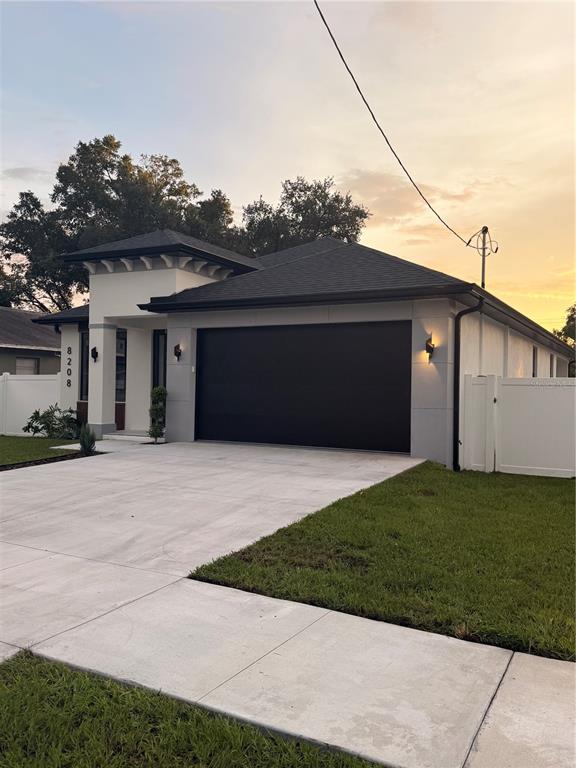 A modern single-story house features a black garage door, white exterior walls, and a driveway — 8208 N ELMER STREET, TAMPA, FL