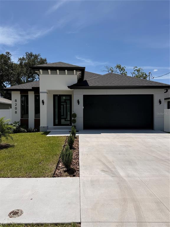 A modern single-story house features a black garage door, white exterior walls, and a glass door — 8208 N ELMER STREET, TAMPA, FL