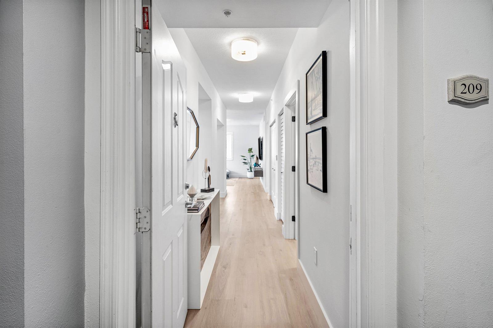 A bright hallway features light wood flooring, white walls, and two ceiling light fixtures — 250 NE 3rd Avenue # 1209, Delray Beach FL 33444, DELRAY BEACH, FL