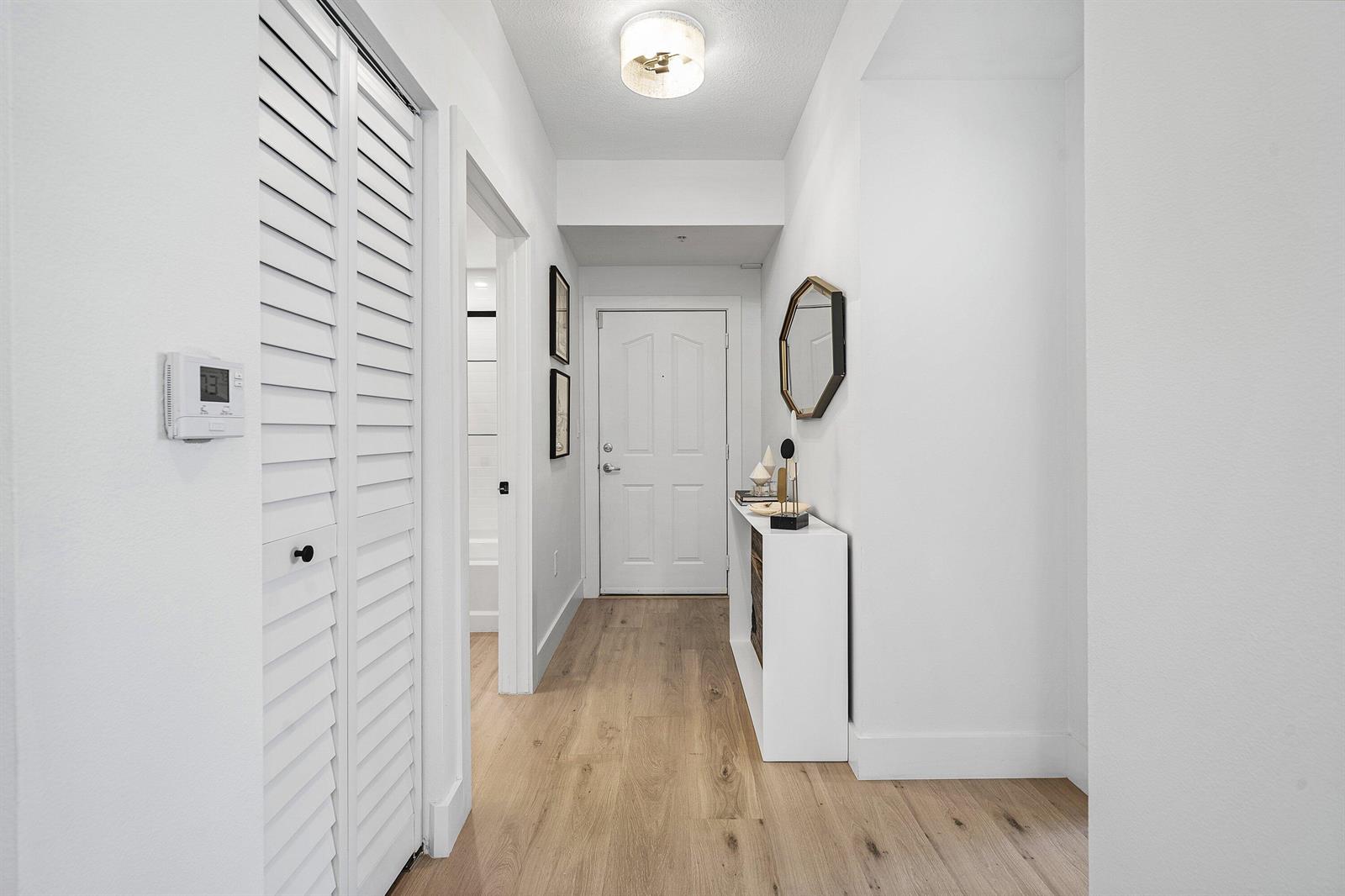 A bright hallway features light wood flooring, white walls, a closet, and a console table — 250 NE 3rd Avenue # 1209, Delray Beach FL 33444, DELRAY BEACH, FL