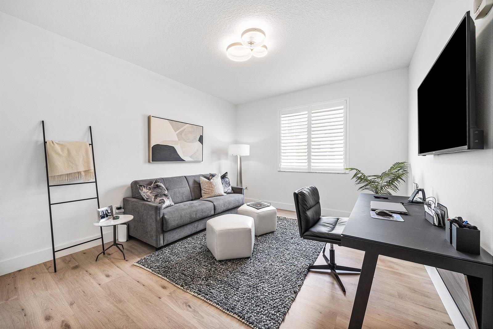 A modern home office features a gray sofa, a black desk, and a textured rug — 250 NE 3rd Avenue # 1209, Delray Beach FL 33444, DELRAY BEACH, FL