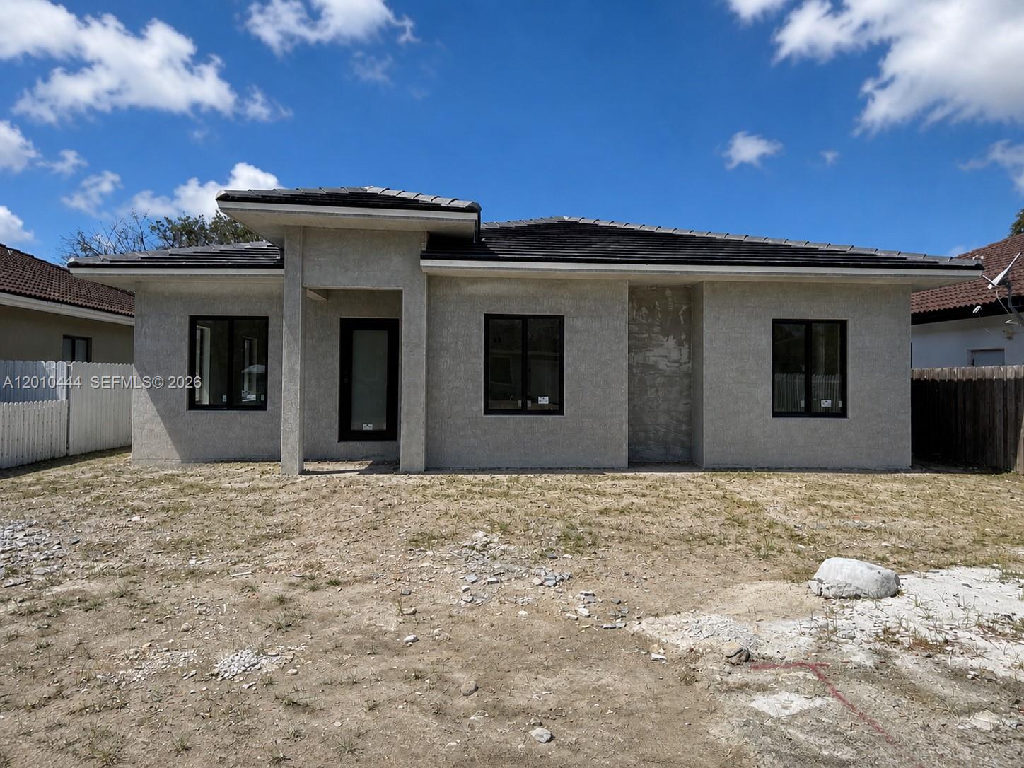 A newly constructed single-story house with a gray stucco exterior and dark-framed windows — 22464 SW 109th Psge, Miami FL 33170, MIAMI, FL
