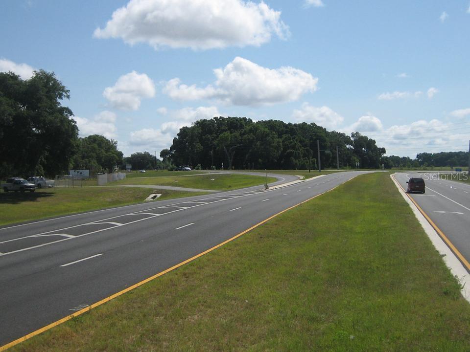 A view of a multi-lane highway stretching toward a treeline under a blue sky — 00 SE 132 St ROAD, BELLEVIEW, FL