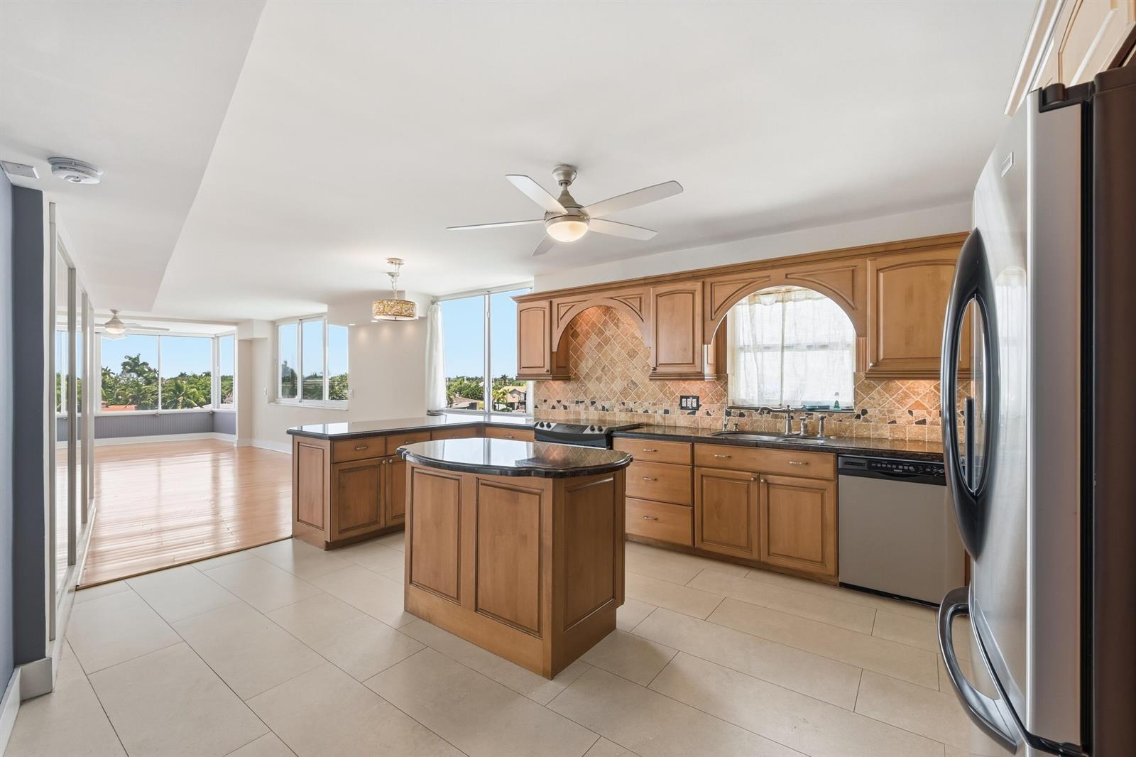A sunroom with hardwood floors and gray wainscoting overlooks a canal with waterfront homes — 401 N Riverside Drive # 408, Pompano Beach FL 33062, POMPANO BEACH, FL