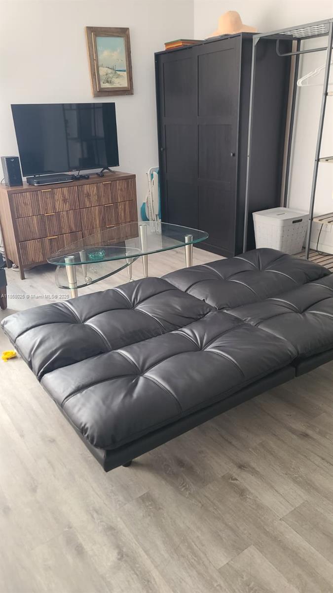 A living room features a black futon, a glass coffee table, and a wooden media console — 3710 Collins Ave # 309, Miami Beach FL 33140, MIAMI BEACH, FL