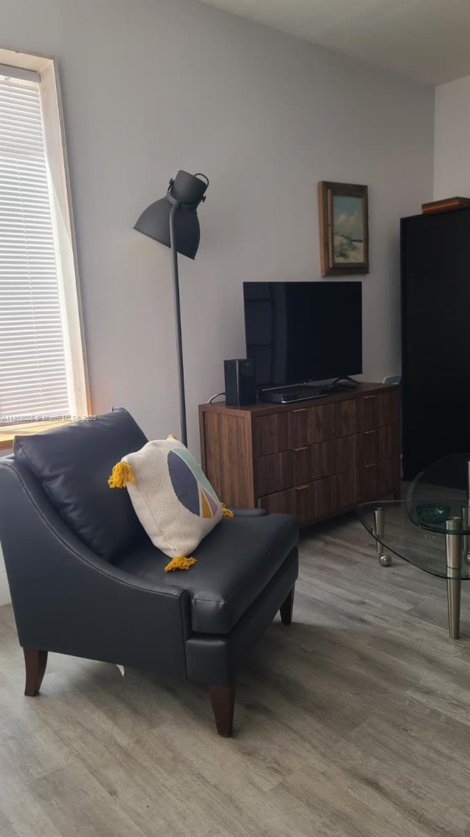 A living room features a dark leather armchair, a wooden dresser with a television, and a floor lamp — 3710 Collins Ave # 309, Miami Beach FL 33140, MIAMI BEACH, FL