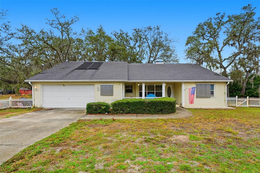 A single-story house with yellow siding, a two-car garage, and a solar panel on the roof — 12227 TERRA CEIA AVENUE, NEW PORT RICHEY, FL