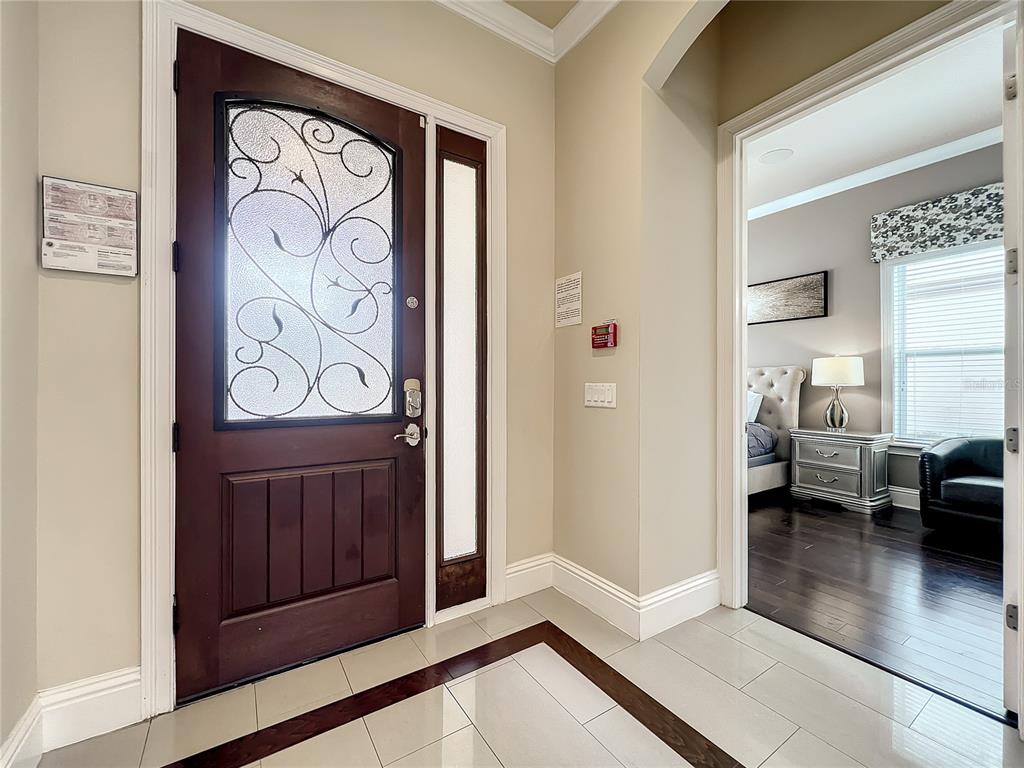 An entryway with a dark wood front door, glass sidelight, and tile flooring — 760 GOLDEN BEAR DRIVE, REUNION, FL
