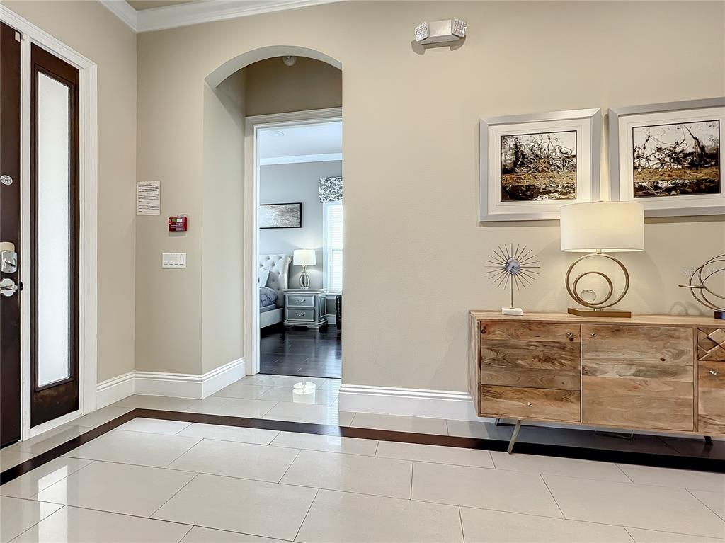 An entryway with tile flooring, a wooden console table, and an arched doorway to a bedroom — 760 GOLDEN BEAR DRIVE, REUNION, FL
