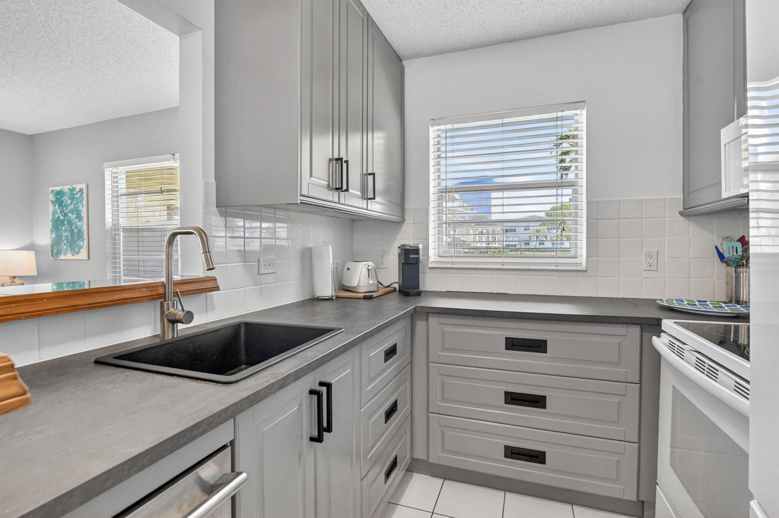 A kitchen features gray cabinets, dark countertops, a black sink, and white subway tile backsplashes — 492 W Tilford, Deerfield Beach FL 33442, DEERFIELD BEACH, FL