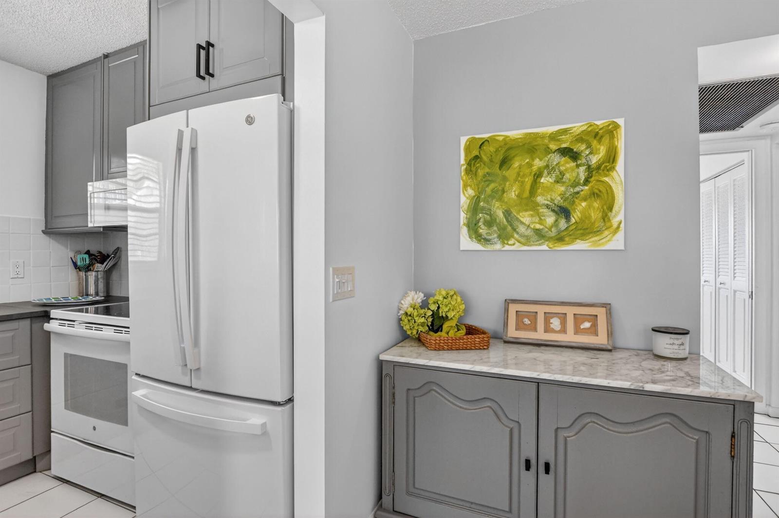 A kitchen features gray cabinets, a white refrigerator, and a marble-topped sideboard with decor — 492 W Tilford, Deerfield Beach FL 33442, DEERFIELD BEACH, FL